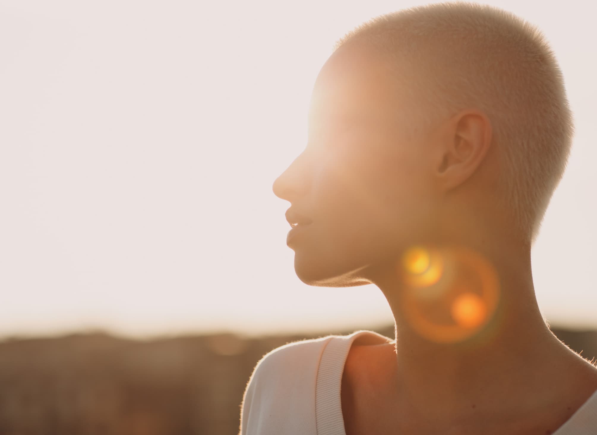 A person in profile, backlit by low evening sun